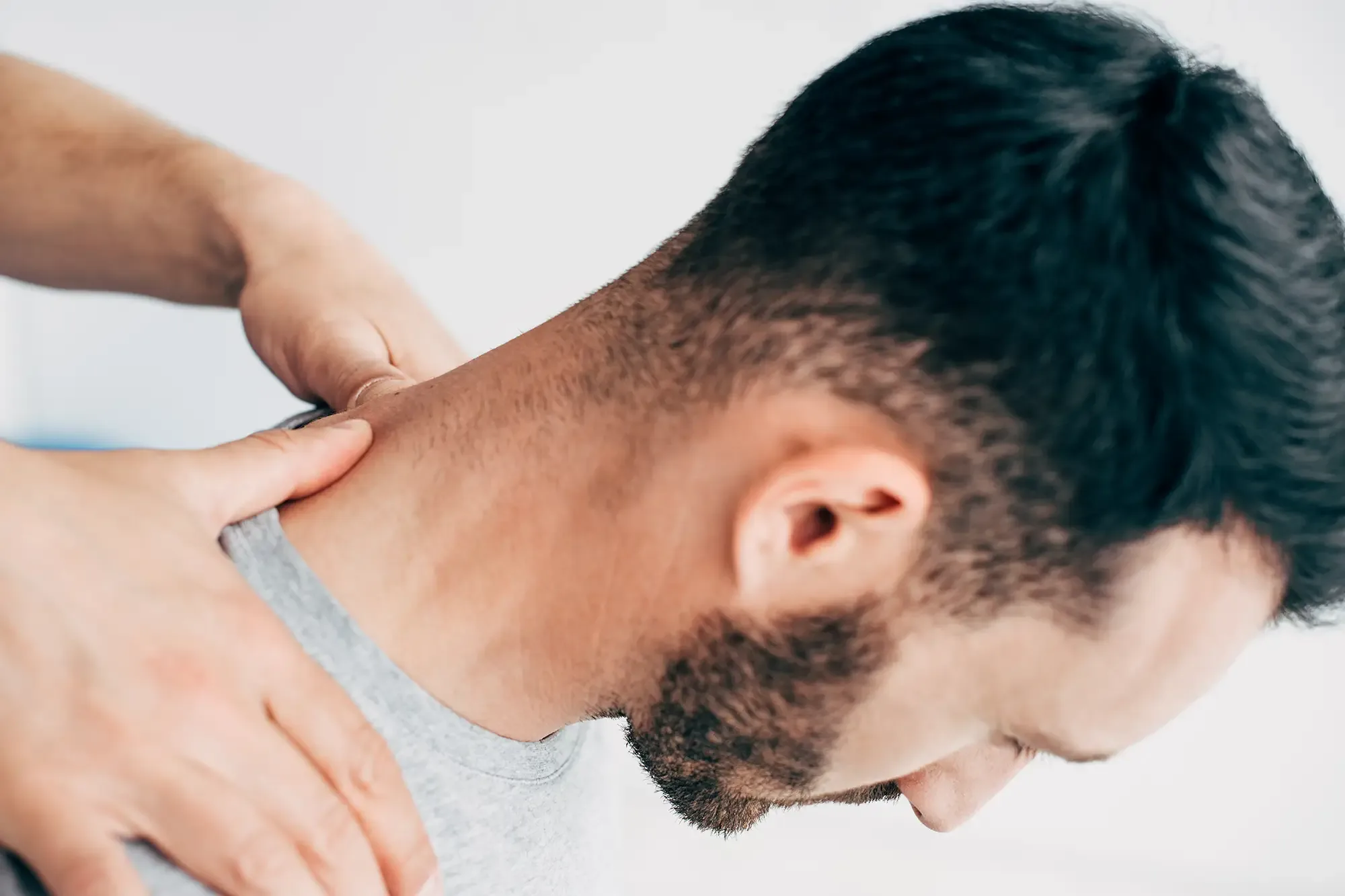 A close-up of a hand pressed to the back of a man&rsquo;s neck