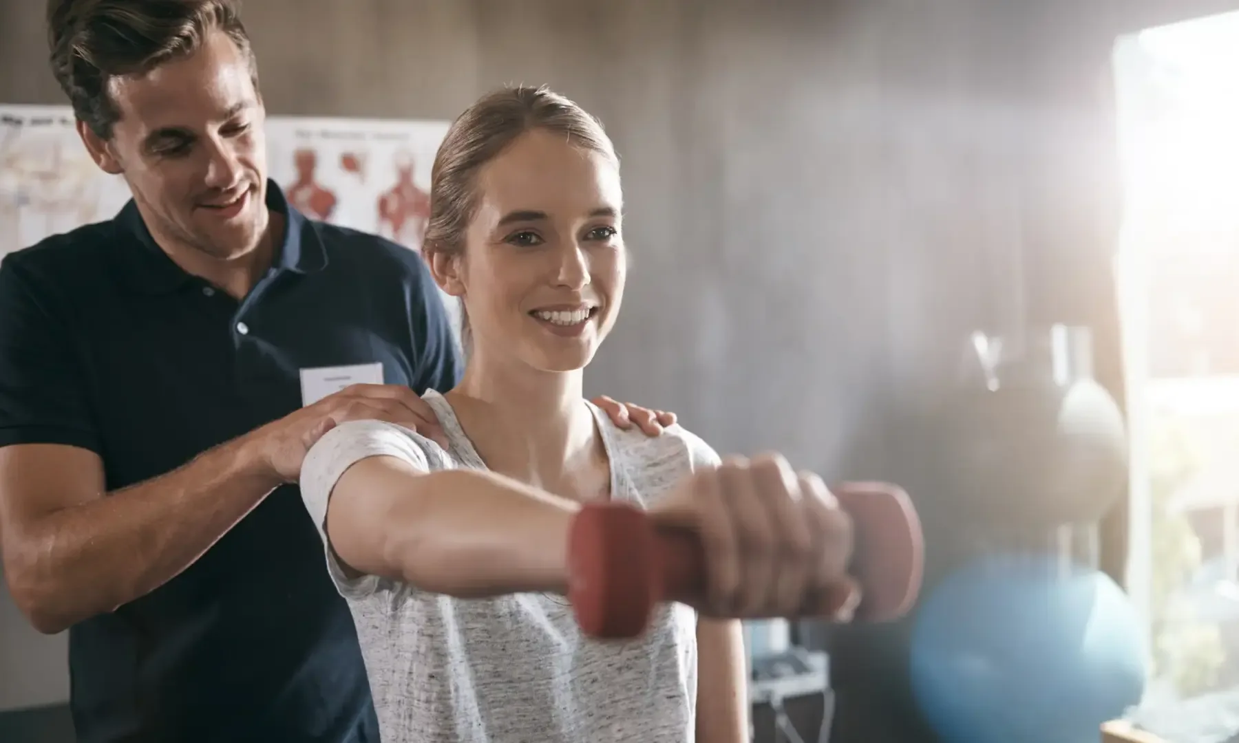A therapist coaching a patient through a dumbbell exercise at King Physical Therapy and Fitness