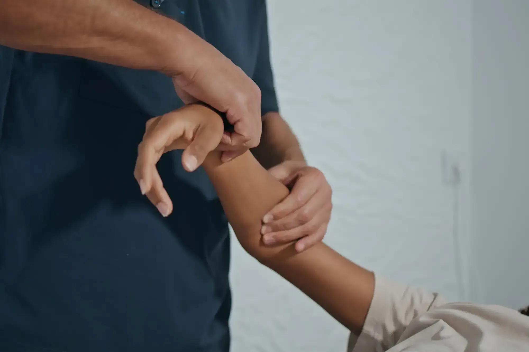 Close-up of a therapist&rsquo;s hands working a patient&rsquo;s elbow and forearm