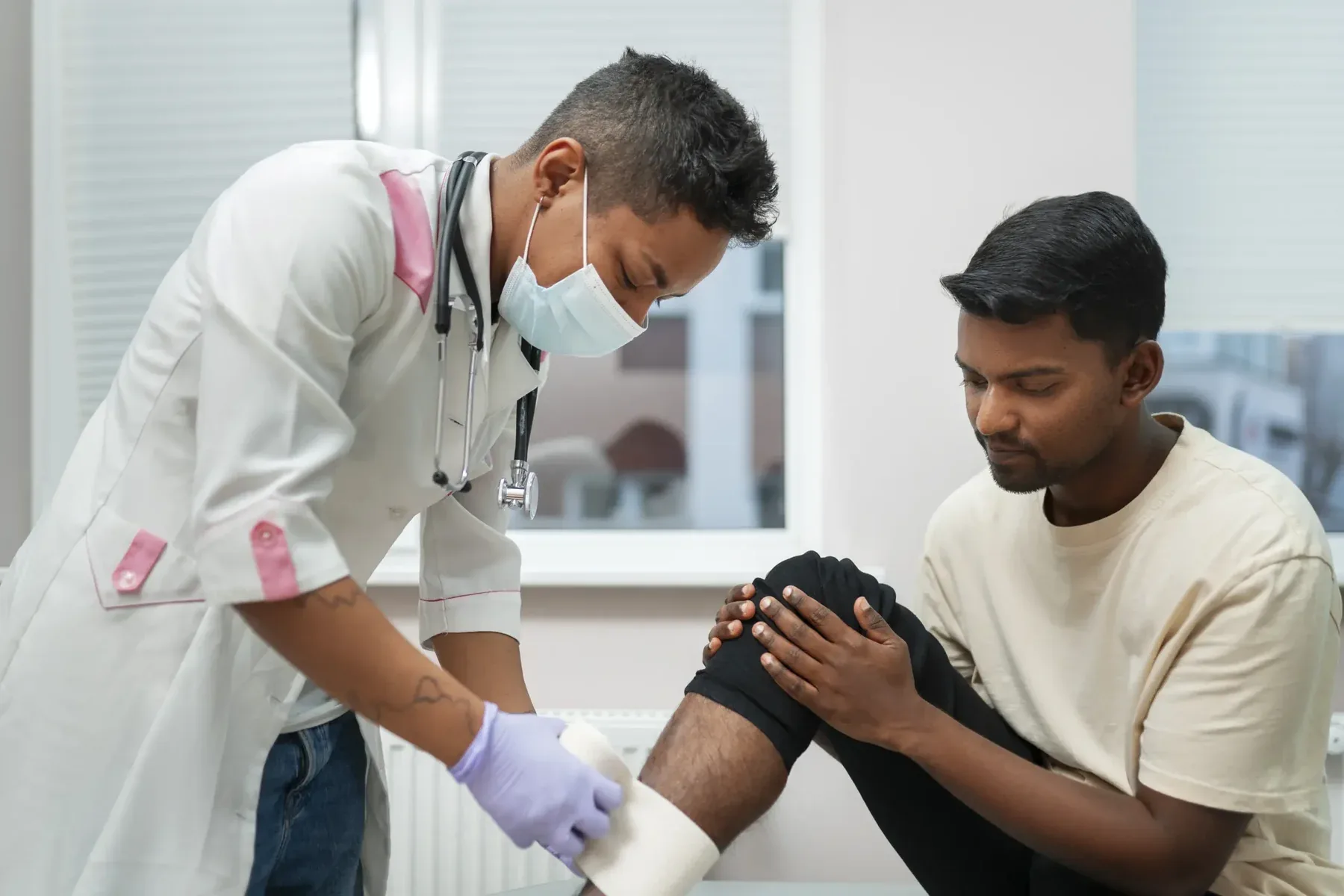 Clinician examining a seated patient&rsquo;s knee during an orthopedic evaluation