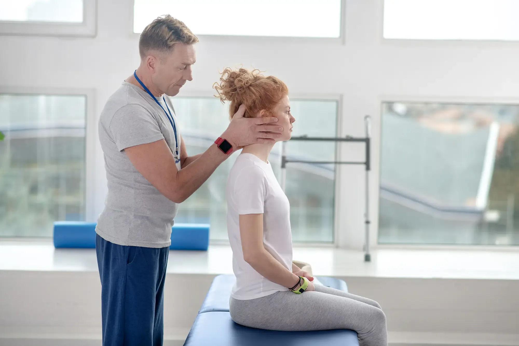 Therapist positioning a seated woman&rsquo;s head during a vestibular assessment