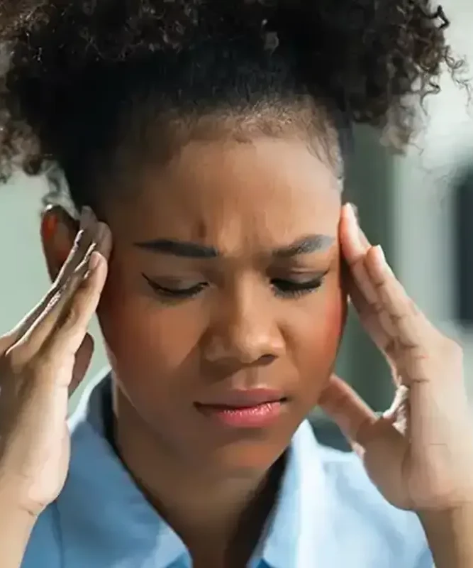 A woman pressing her temples with both hands during a headache, evaluated at King Physical Therapy and Fitness in Connellsville, PA