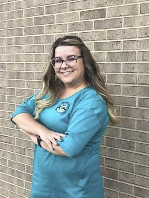 Dana Weimer, Billing/Office Coordinator at King Physical Therapy & Fitness, smiling in a teal top against a brick wall, showcasing her friendly demeanor and professionalism.